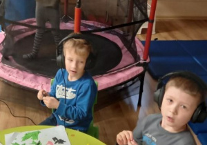 Chłopcy wyklejają plasteliną, a dziewczynka skacze na trampolinie