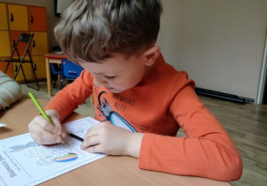 Chłopiec koloruje kolorowankę