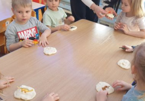 Dzieci odciskają figurkę dinozaura w masie solnej tworząc "skamieliny"