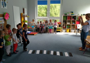 Dzieci trenują przejście przez pasy w sali przedszkolnej