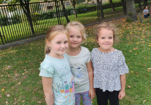 trzy dziewczynki uśmiechają się w ogródku