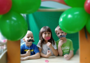Trójka dzieci pozuje w foto budce