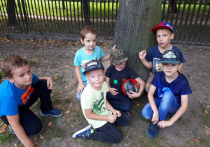 Chłopcy z piłką siedzą pod drzewem
