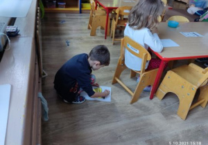 Chłopiec rysuje na podłodze