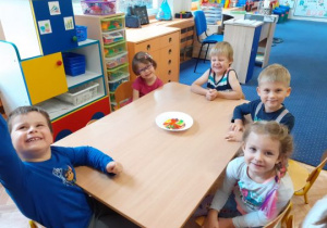 Dzieci siedzą przy stoliku i się uśmiechają