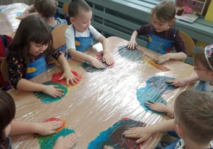 Dzieciza pomocą dłoni mieszają kolory