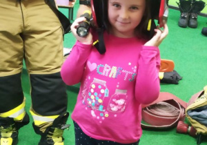 Dziewczynka prezentuje hełm strażacki