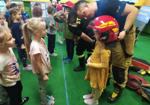 Strażak zakłada dziewczynce hełm strażacki