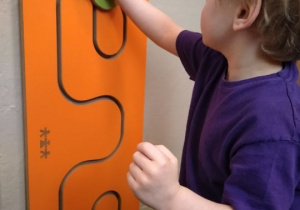 Chłopiec wykonuje ćwiczenia na tablicy manipulacyjnej