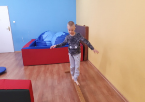 Chłopiec wykonuje ćwiczenia równoważne