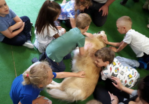 Dzieci głaszczą i przytulają psa