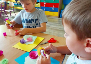 Dzieci przyklejają papierowe kwiaty