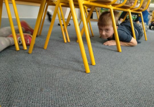 Chłopiec czołga się pod krzesłem