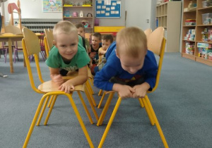 Dzieci chodzą na czworaka po krzesełkach
