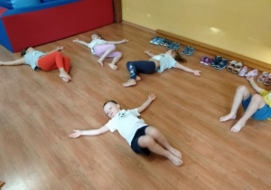 Dzieci wykonują ćwiczenia w pozycji leżącej