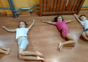 Dzieci wykonują ćwiczenia w pozycji leżącej