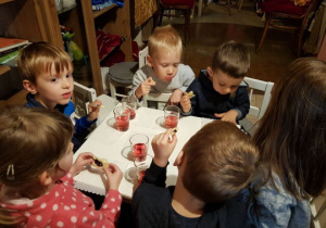 Dzieci siedzą przy stoliku z soczkiem i ciasteczkami