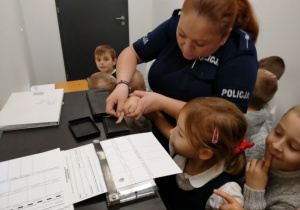 Policjantka bierze odciski palców od dziewczynki