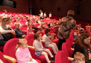 Dzieci siedzą w fotelach teatralnych