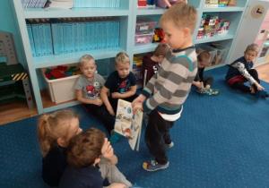 Chłopiec pokazuje innym dzieciom książkę