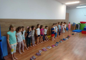 Dzieci stoją w rzędzie przed swoimi butami