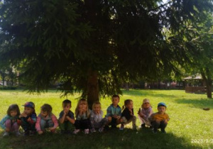 Dzieci siedzą pod drzewem