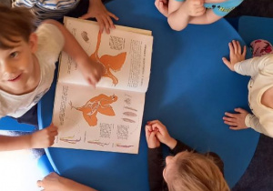 Dzieci oglądają książkę przy stoliku