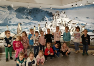 Dzieci pozują na tle wystawy pingwinów
