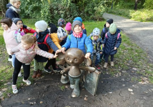 Dzieci trzymają figurę plastusia za ucho