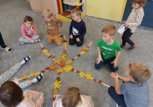 Dzieci na dywanie wykonują pracę przestrzenną z darów jesieni