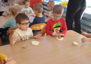 Dzieci odciskają figurkę dinozaura w masie solnej tworząc "skamieliny