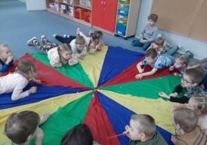 Dzieci wykonują ćwiczenia oddechowe leżąc na chuście animacyjnej