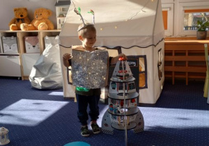 Chłopiec przebrany za kosmitę bawi się rakietą
