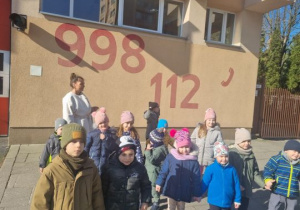 Dzieci stoją przed budynkiem straży pożarnej