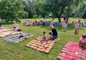 Dzieci wykonują zadanie na kocach z zamkniętymi oczami