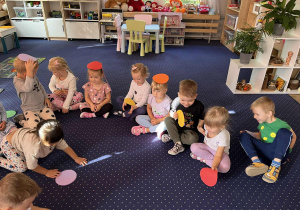 Dzieci siedzą na dywanie z kropkami na głowie