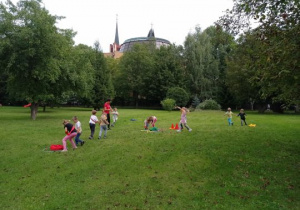Dzieci wykonują ćwiczenia ruchowe w ogrodzie przedszkolnym