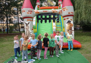 Dzieci stoją przed dmuchanym zamkiem