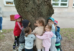 Dzieci przytulają się do drzewa