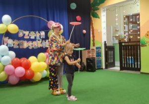 Dziewczynka z artystką kręcą talerzykami na patyku