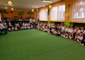 Dzieci siedzą w oczekiwaniu na rozpoczęcie uroczystości