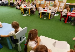 Dzieci siedzą przy stolikach