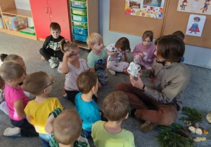 Dzieci siedzą na dywanie i przyglądają sie replice czaszki wilka