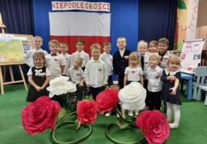 Dzieci pozują do zdjęcia na tle flagi polski