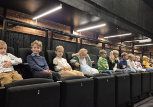 Dzieci siedzą w fotelach w oczekiwaniu na przedstawienie