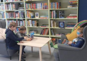 Dzieci siedzą w fotelach i oglądają książki