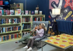 Dzieci siedzą w fotelach i oglądają książki