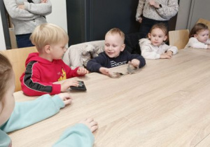 Chłopcy oglądają legitymację policyjną i kajdanki