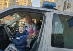 Dzieci siedzą w radiowozie
