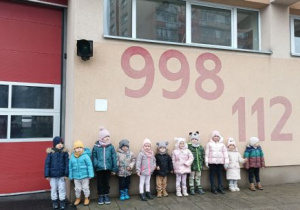 Dzieci stoją przed remizą strażacką